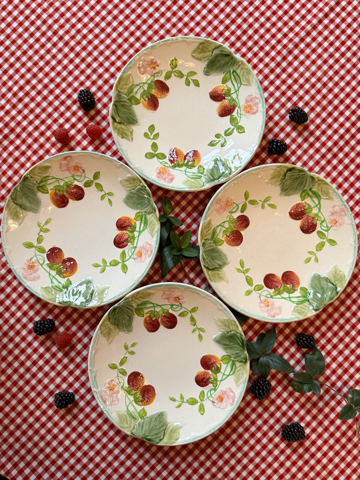 Suite de quatre assiettes en barbotine à décor de fraises