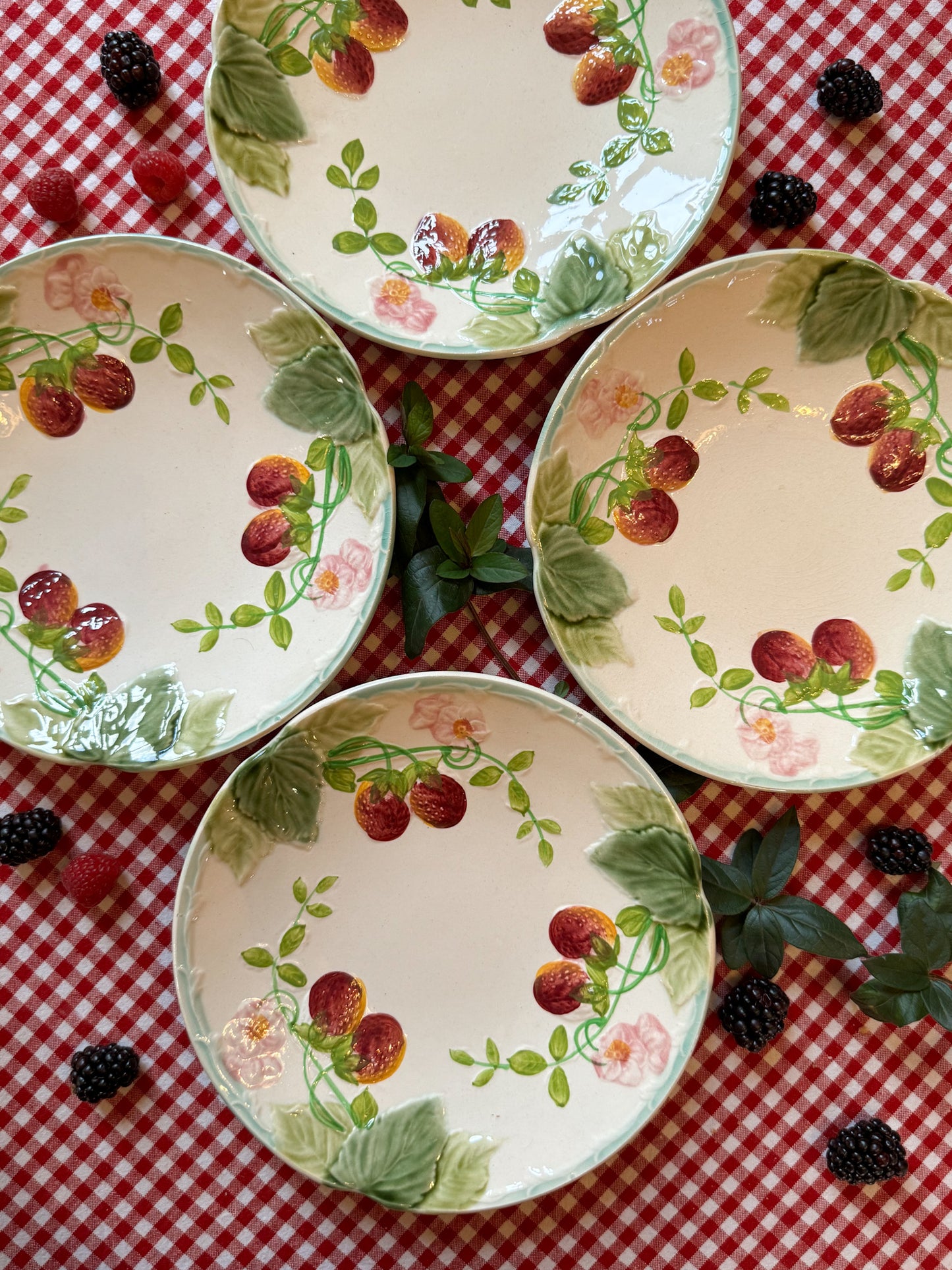 Suite de quatre assiettes en barbotine à décor de fraises