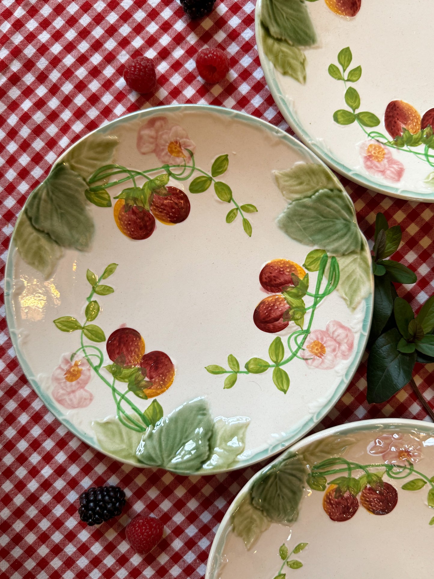 Suite de quatre assiettes en barbotine à décor de fraises
