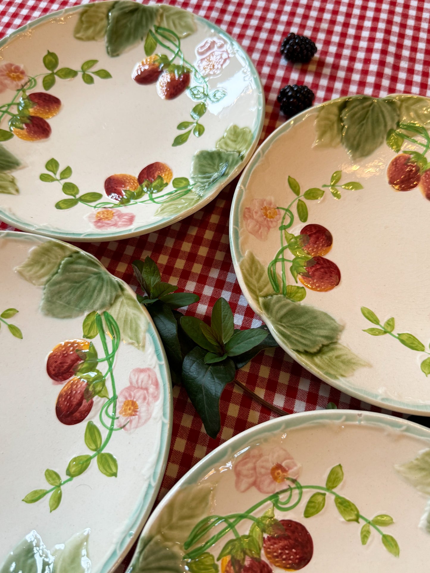 Suite de quatre assiettes en barbotine à décor de fraises